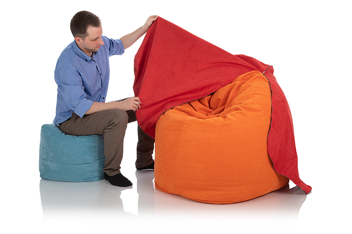 Junger Mann zieht einen roten Sitzsack-Bezug über einen Sitzsack orange