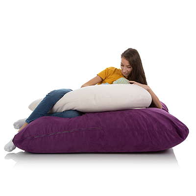 Junge Frau liegt auf einem XXL Bodenkissen violett mit einem weissen Stillkissen
