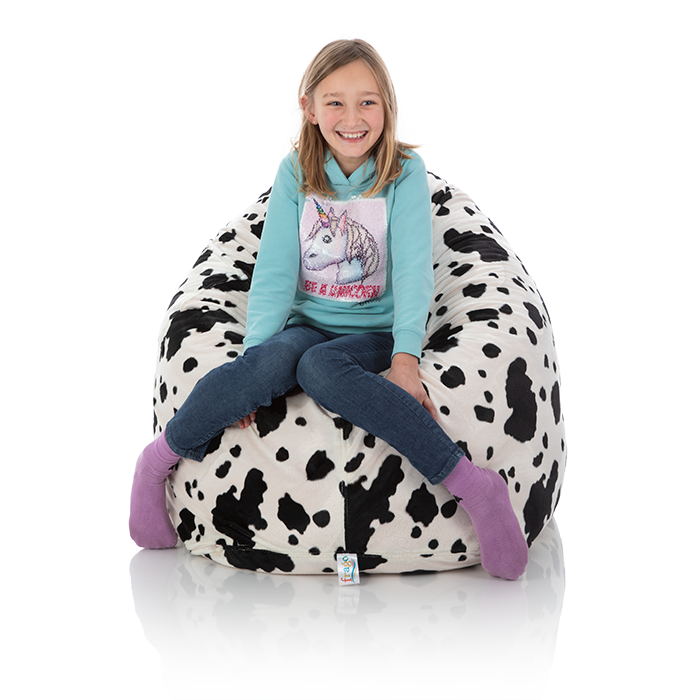 Junges Maedchen sitzt im Kinder-Sitzsack Sunny mit Kuh-Muster